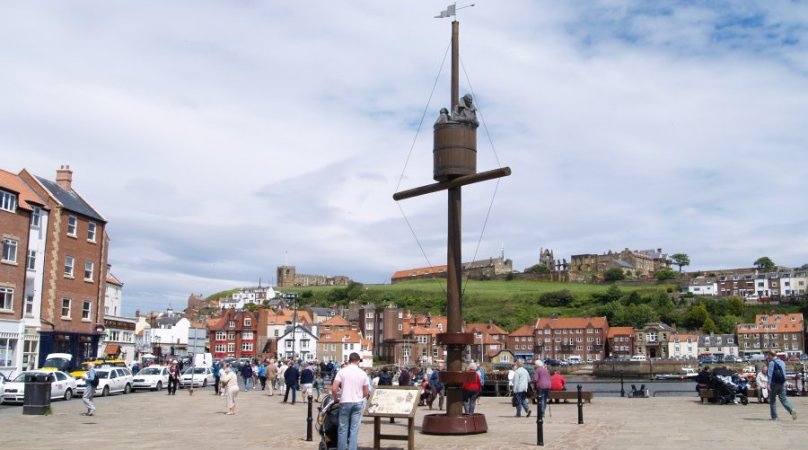 Location 18a: View of the harbour from outside of Whitby station. We can now head along by the harbour and climb up to St Mary's Church and Whitby Abbey on the distant horizon.