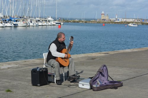Musician playing on the quayside of Howth Harbour Howth, Ireland