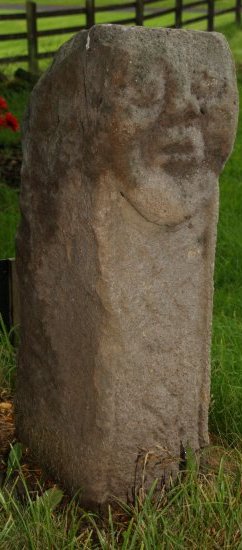 64. Carved stones in the churchyard Killadeas Church (Church of Ireland), Co. Fermanagh, Northern Ireland (NI). On the left is the Bishop's Stone with a pagan head on one side (9th-11th century, bishop with bell and crozier on reverse), in the middle a Cross Slab Stone and on the right the Pillar standing stone (possibly a prehistoric phallic pagan standing stone)