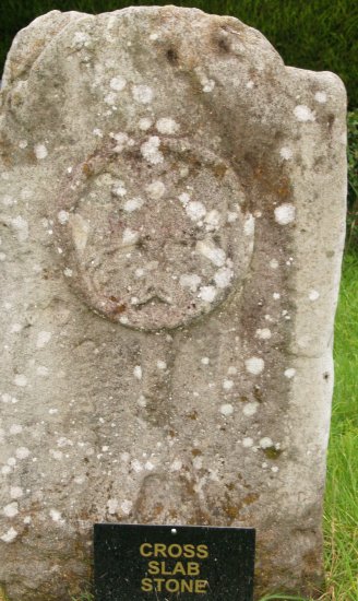 64. Carved stones in the churchyard Killadeas Church (Church of Ireland), Co. Fermanagh, Northern Ireland (NI). On the left is the Bishop's Stone with a pagan head on one side (9th-11th century, bishop with bell and crozier on reverse), in the middle a Cross Slab Stone and on the right the Pillar standing stone (possibly a prehistoric phallic pagan standing stone)