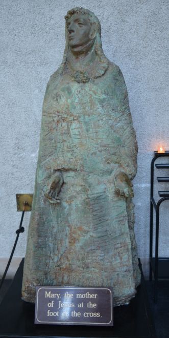 statue of Mary, the mother of Jesus, at the foot of the cross modern Coventry Cathedral new