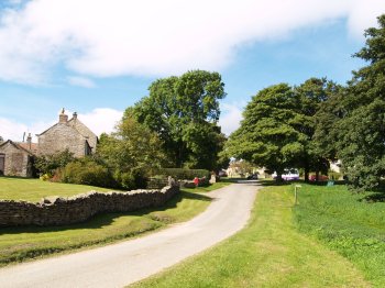 Looking up the tree lined street of Cold Kirby village - Walking from Sutton Bank National Park Visitor Centre, North York Moors National Park, North Yorkshire, Northern England